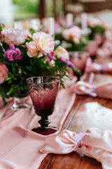 Vintage festive table setting with pink roses, candles and cutlery on an old wooden board