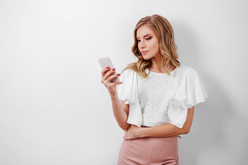 Portrait of a smiling casual woman holding smartphone over white background