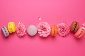 multi-colored macarons with cream and a pink rose bud
