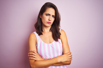Obraz premium Young beautiful woman wearing striped pink swimsuit swimwear over pink isolated background skeptic and nervous, disapproving expression on face with crossed arms. Negative person.