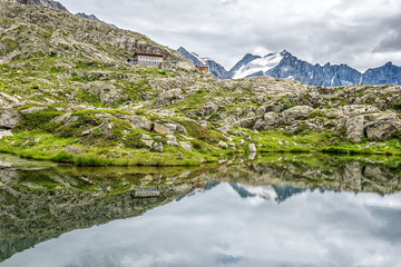 Rifugio Mandron - Citt&agrave; di Trento (mt. 2449 a.s.l.) mirrored in a nearby lake. In the background the Presena glacier. Trentino Alto Adige, Italy - July 2019