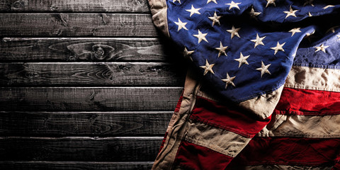 Old and worn American flag on dark wooden background