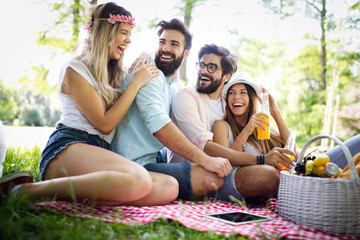 Happy friends in the park having picnic on a sunny day.