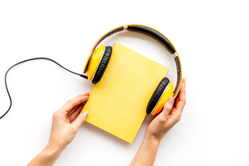 workplace with books and hands, headphones on white background flatlay