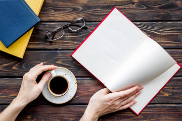 workplace with book in hands for reading, glasses, coffee on wooden background flatlay mockup