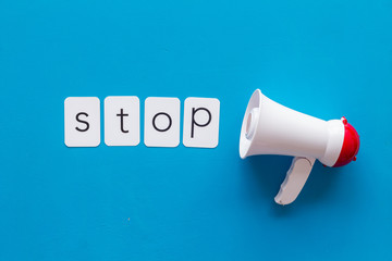 Stop announcement symbol with megaphone and text on blue background top view