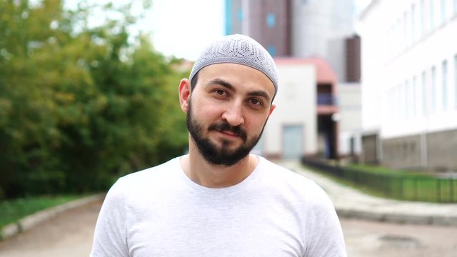 Bearded muslim man in city looking at camera