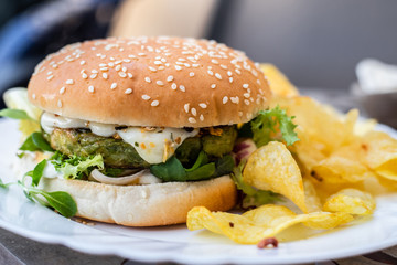 Hamburger vegetarian burger with green vegetables salad and cheese tofu cheese all vegan food with chips potato in blurred background