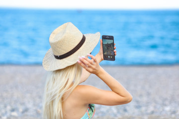  Young girl plays with phone, sunbathing on beach