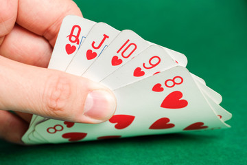 Hand holds a combination in poker - straight flush on a green background.