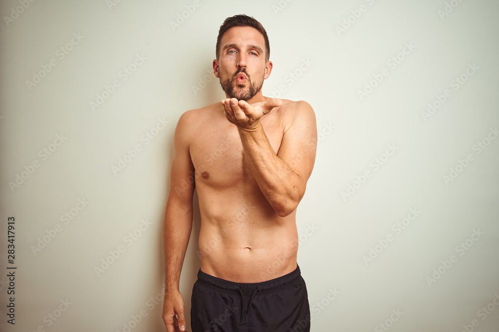 Sticker young handsome shirtless man over isolated background looking at the camera blowing a kiss with hand