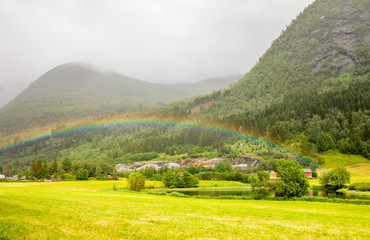 Fototapeta na wymiar Colorful rainbow over the fields, lake and houses of Skei village, Jølster in Sogn og Fjordane county, Norway.
