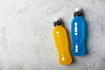 Isotonic energy drink. Bottles with blue and yellow transparent liquid, sport beverage on a gray...