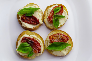 Tasty bruschettas with sun-dried tomatoes on light background