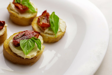 Tasty bruschettas with sun-dried tomatoes on light background