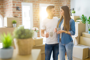 Beautiful couple moving to a new house, smiling cheerful drinking a cup of coffee