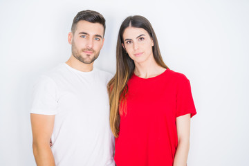 Young beautiful couple together over white isolated background with serious expression on face. Simple and natural looking at the camera.