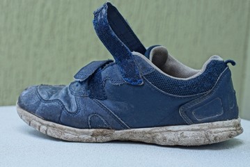 one old blue and dirty sneaker stands on a white table