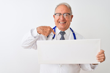 Senior grey-haired doctor man holding banner standing over isolated white background with surprise face pointing finger to himself