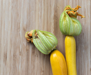 Two yellow fresh zucchini on a light brown background, top view