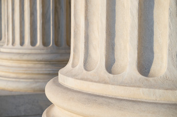 White marble neoclassical columns in soft sunset light at the Supreme Court Building in Washington...