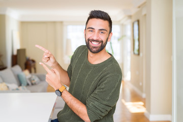 Handsome man pointing with arms and fingers, smiling cheerful with big smile on face