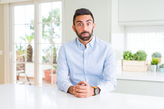 Handsome hispanic business man puffing cheeks with funny face. Mouth inflated with air, crazy expression.