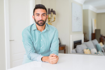 Handsome hispanic man at home with serious expression on face. Simple and natural looking at the camera.