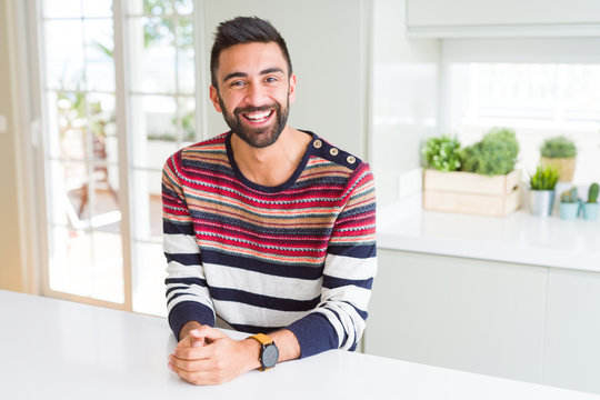 Handsome hispanic man wearing stripes sweater at home with a happy and cool smile on face. Lucky person.