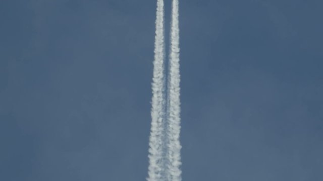 Flying jet airliner leaving contrain in the blue sky. 4K telephoto lens clip