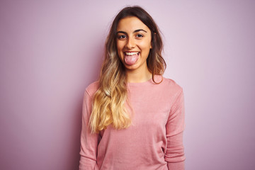 Fototapeta premium Young beautiful woman wearing a sweater over pink isolated background sticking tongue out happy with funny expression. Emotion concept.