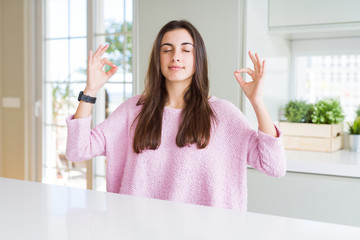 Beautiful young woman wearing pink sweater relax and smiling with eyes closed doing meditation...