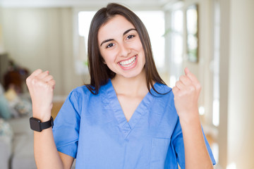 Beautiful young nurse woman at the clinic celebrating surprised and amazed for success with arms raised and open eyes. Winner concept.