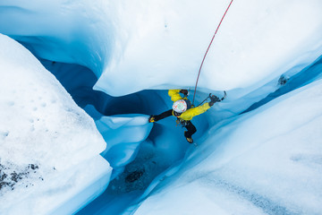 Ice climber stemming off a vertical pillar of ice inside a moulin on the Matanuska Glacier.