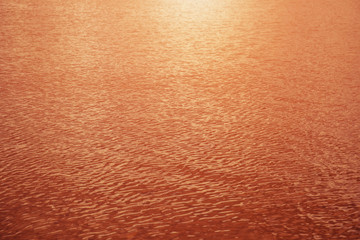 Orange wavy water surface ripple background, sunset