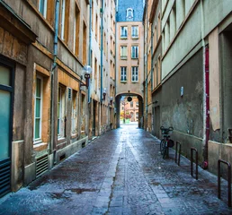 Wall murals Narrow Alley Colorful empty narrow cobblestone alley through old buildings to archway