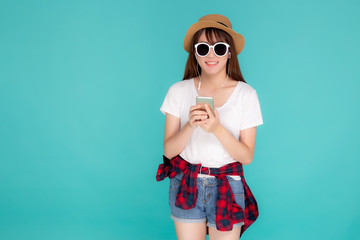 Beautiful portrait young asian woman listening music on phone with earphone isolated on blue background, asia girl using smartphone excited and fun with relax in travel summer trip concept.