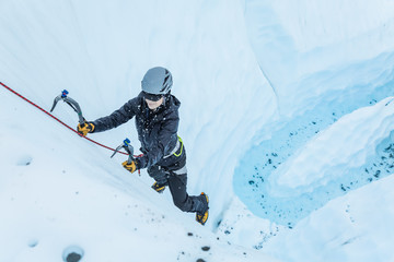 Flying ice as woman swings an ice tool into the glacier ice climbing in Alaska.