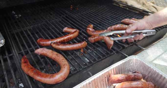 A close up shot of a grill with links of kielbasa cooking.  	