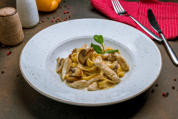 Pasta with chicken and mushrooms on dark rustic background