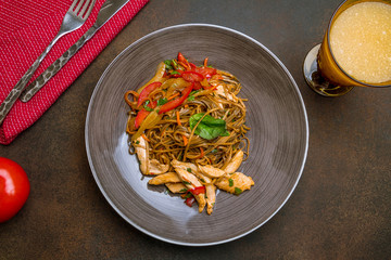 chicken wok noodles on dark rustic background