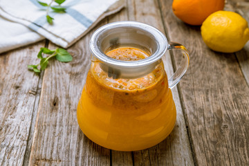 sea buckthorn tea in the teapot on wooden background