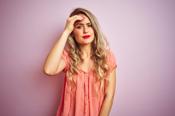 Young beautiful woman wearing t-shirt standing over pink isolated background worried and stressed about a problem with hand on forehead, nervous and anxious for crisis