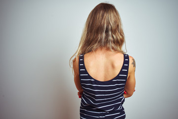 Young beautiful woman wearing stripes t-shirt standing over white isolated background standing backwards looking away with crossed arms