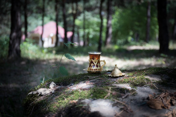 Eastern black tea in glass at the forest. Eastern tea concept. Armudu traditional cup. Green nature background.