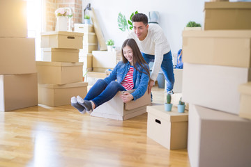 Funny asian couple having fun, riding inside cardboard box smiling happy, very excited moving to a new house