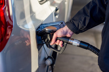 A man hand holding pump filling gasoline. Pumping petrol into the tank. A car refuel on gas station