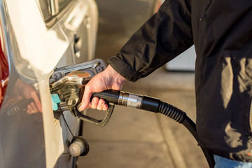 A man hand holding pump filling gasoline. Pumping petrol into the tank. A car refuel on gas station