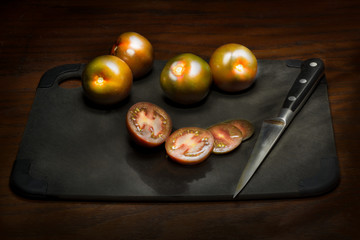 Ripe tomatoes sliced on cutting board.