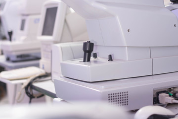 Close up of digital white Ophthalmoscope and tonometer instruments in ophthalmologists room with blank screen monitor